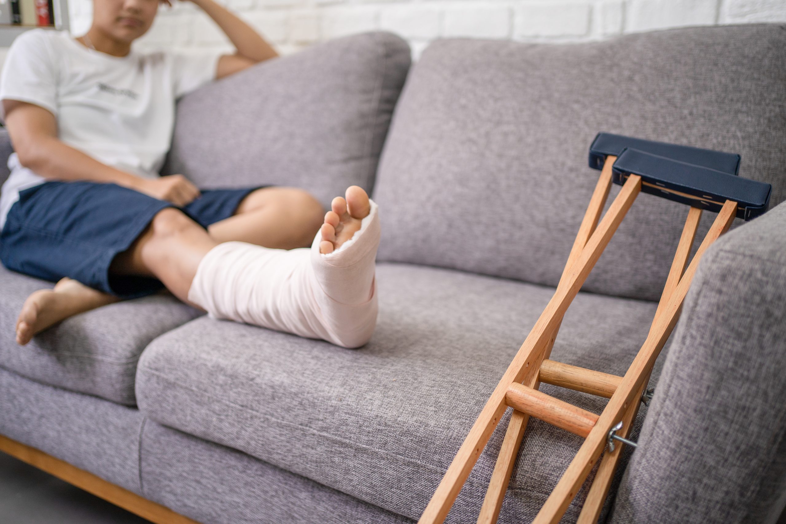 A man with a broken leg sits on a couch after calling a Personal Injury Lawyer Peoria IL