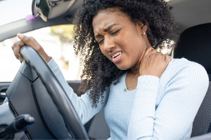A woman holds her neck after getting into a car accident, which means it's  time to contact Rochford & Associates, a Car Accident Lawyer in Peoria IL