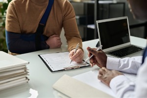 A victim in a sling signs paperwork after looking for a Truck Accident Lawyer in Peoria IL