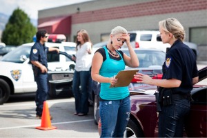 A woman holds her head and talks to police after getting into an accident. If you need a Truck Accident Lawyer in East Peoria IL, call Rochford & Associates.
