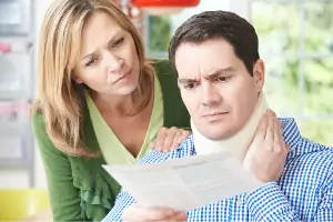 A man holds his neck while he and his wife review legal paperwork. If you've been involved in Trucking Accidents in Peoria IL, let Rochford & Associates help.
