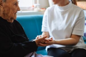 A woman holds an elderly man's hand. Rochford & Associates are Nursing Home Abuse Lawyers in East Peoria IL.