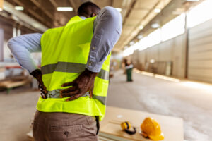 Workplace & Premises Liability 2 A man holds his back after getting injured on the job, making it time to call the workplace & premises liability attorneys Peoria trusts